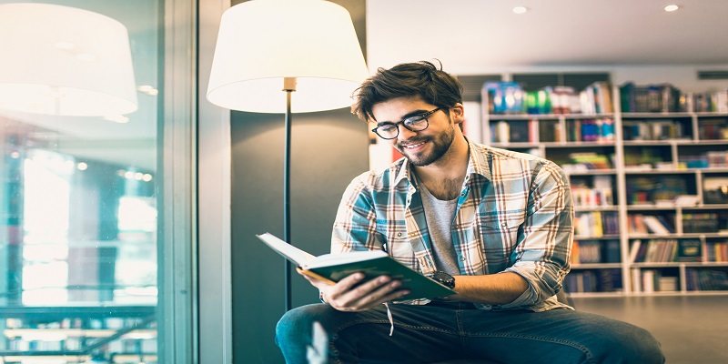 Young man reading book in the library