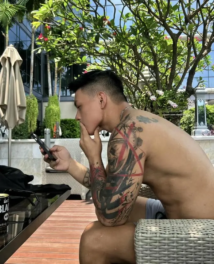 Anh chàng lực lưỡng hình xăm cá tính đang dùng điện thoại Anh chàng lực lưỡng hình xăm cá tính đang dùng điện thoại