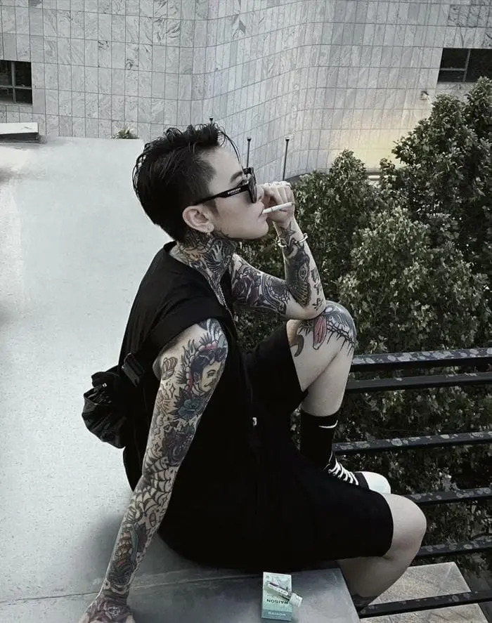 Chàng trai phong trổ hình xăm cá tính ngồi ngoài phố Chàng trai phong trổ hình xăm cá tính ngồi ngoài phố